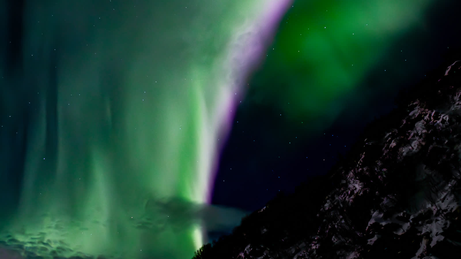 Aurore boréale au-dessus d'une montagne enneigée pendant la nuit polaire, près de Skjervøy